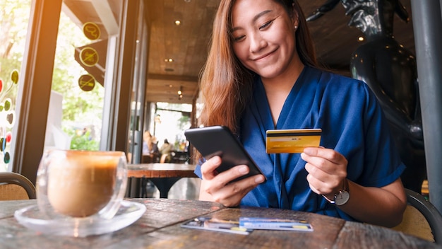 Close-upbeeld van aziatische vrouw die creditcard gebruikt om online op mobiele telefoon te kopen en te winkelen