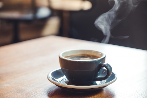 Close-upbeeld van blauwe koppen hete koffie met rook op uitstekende houten lijst in koffie