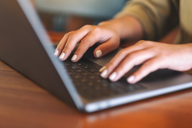 Close-upbeeld van de handen van de vrouw die op laptopcomputertoetsenbord gebruiken en typen