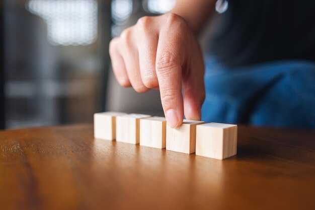 Close-upbeeld van een hand die vijf stukken leeg houten kubusblok kiest en plukt