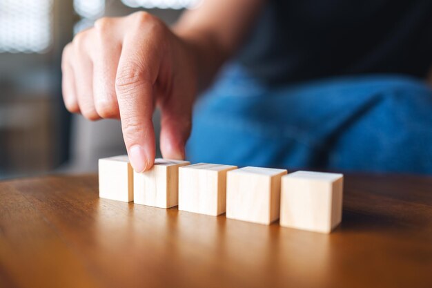 Close-upbeeld van een hand die vijf stukken leeg houten kubusblok kiest en plukt