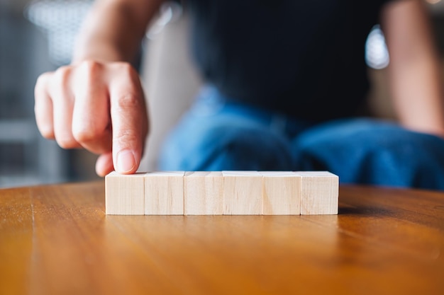 Close-upbeeld van een hand die zes stukken leeg houten kubusblok kiest en plukt