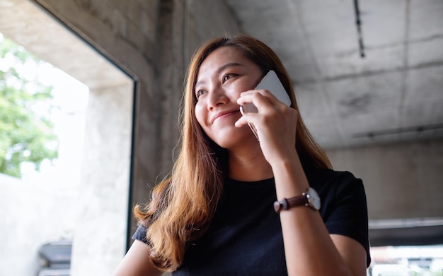 Close-upbeeld van een jonge Aziatische vrouw die op mobiele telefoon spreekt