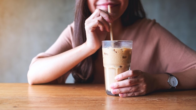 Close-upbeeld van een jonge vrouw die ijskoffie vasthoudt en drinkt