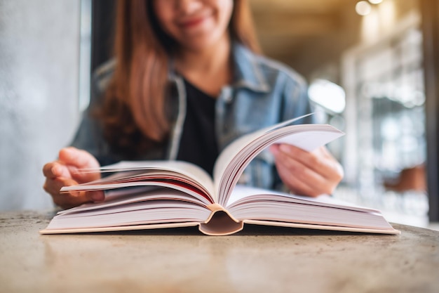 Foto close-upbeeld van een jonge vrouw die zit en een boek leest