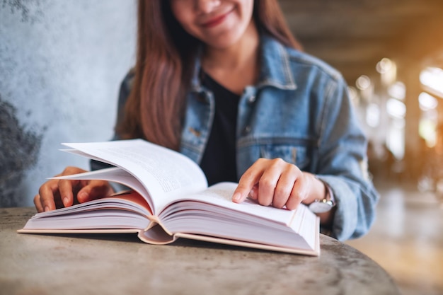 Close-upbeeld van een jonge vrouw die zit en een boek leest