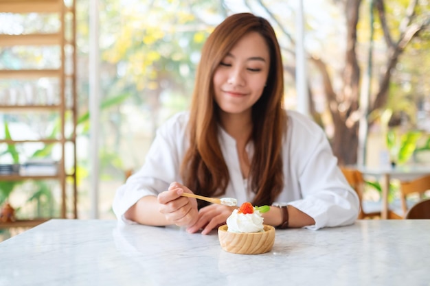 Close-upbeeld van een mooie aziatische vrouw geniet van het eten van een ijsje in restaurant
