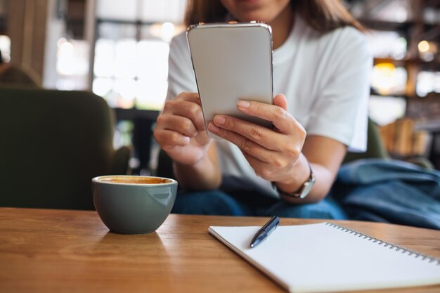 Close-upbeeld van een mooie jonge Aziatische vrouw die mobiele telefoon vasthoudt en gebruikt