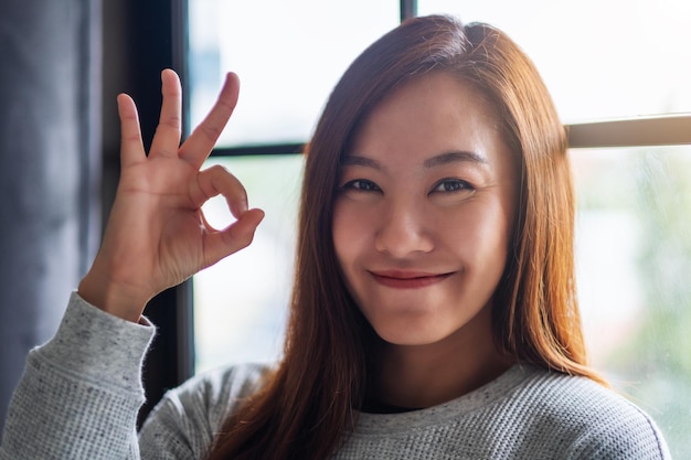 Foto close-upbeeld van een mooie jonge aziatische vrouw die ok handteken maakt en toont