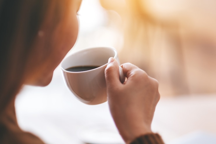 Foto close-upbeeld van een mooie vrouw die hete koffie vasthoudt en drinkt