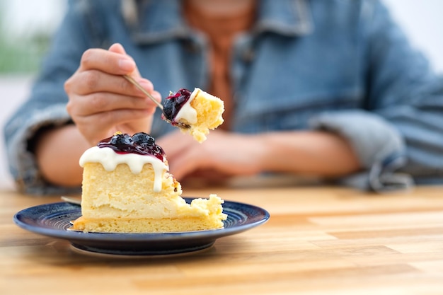 Close-upbeeld van een vrouw die bosbessenkaastaart met lepel eet