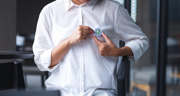 Close-upbeeld van een vrouw die Covid19 gevaccineerde bordbroche op shirt zet