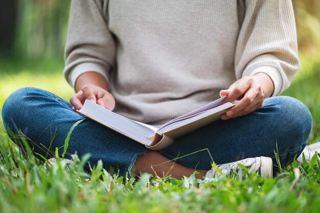 Close-upbeeld van een vrouw die een boek leest terwijl ze in het park zit