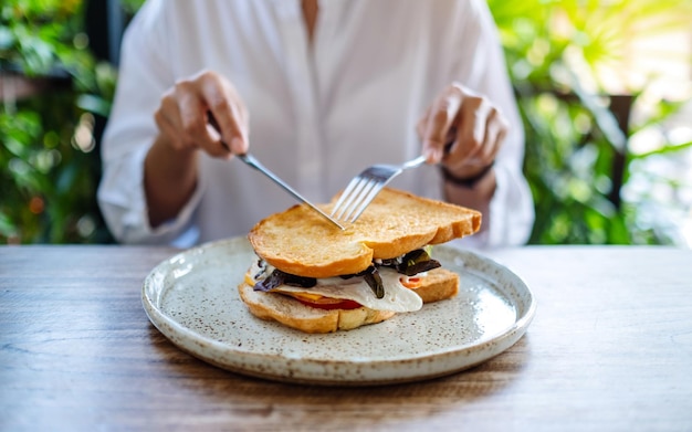 Close-upbeeld van een vrouw die een broodje ham en kaas eet