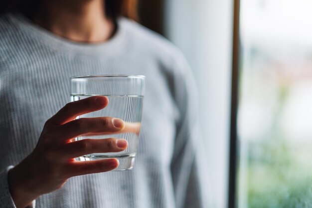 Close-upbeeld van een vrouw die een glas zuiver water vasthoudt