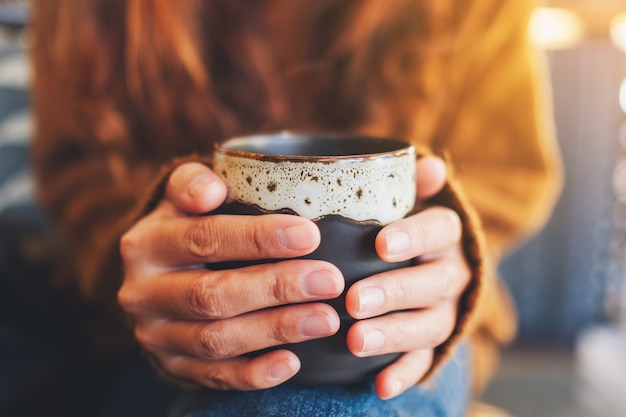 Close-upbeeld van een vrouw die een kop hete koffie houdt