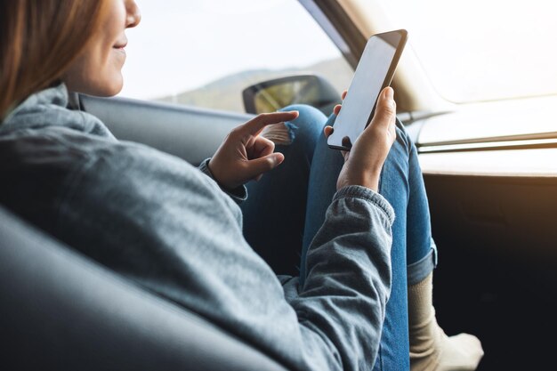 Close-upbeeld van een vrouw die een mobiele telefoon vasthoudt en gebruikt tijdens het autorijden