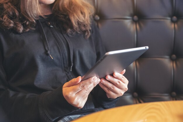 Close-upbeeld van een vrouw die en tabletpc in koffie houdt gebruikt