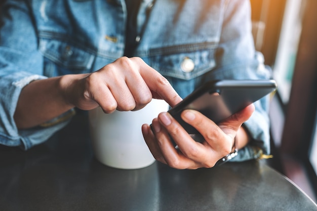 Close-upbeeld van een vrouw die het mobiele telefoonscherm vasthoudt en aanraakt