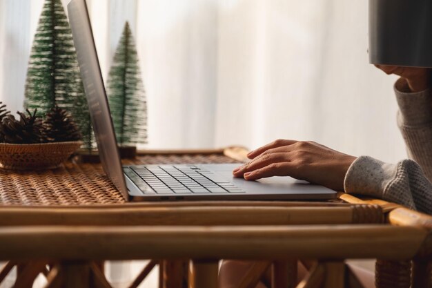 Close-upbeeld van een vrouw die het touchpad van een laptop gebruikt en aanraakt terwijl ze thuis koffie drinkt