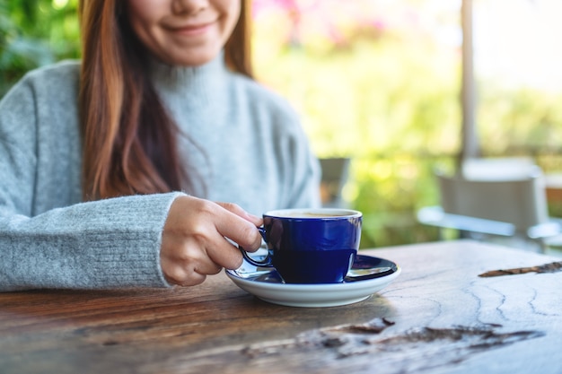 Close-upbeeld van een vrouw die hete koffie in de buitenlucht vasthoudt en drinkt