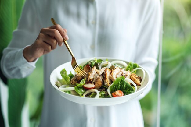 Close-upbeeld van een vrouw die kippensalade vasthoudt en eet
