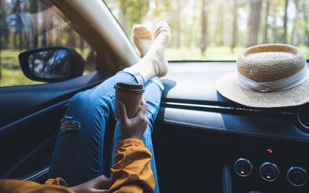 Close-upbeeld van een vrouw die koffie in de auto legt en drinkt