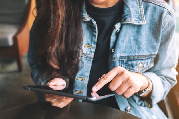 Foto close-upbeeld van een vrouw die tablet-pc vasthoudt en gebruikt terwijl ze in café zit