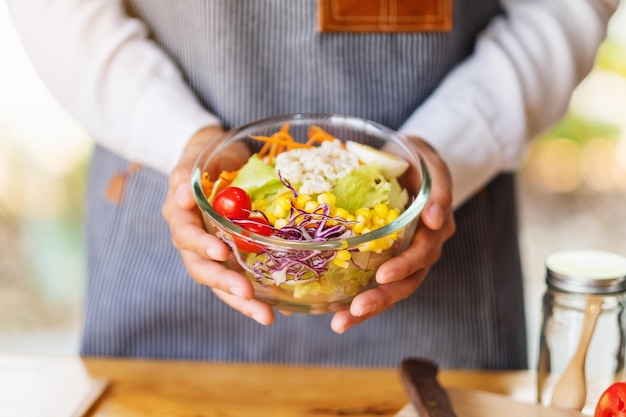 Close-upbeeld van een vrouwelijke chef-kok die een kom verse gemengde groentensalade in keuken kookt en houdt