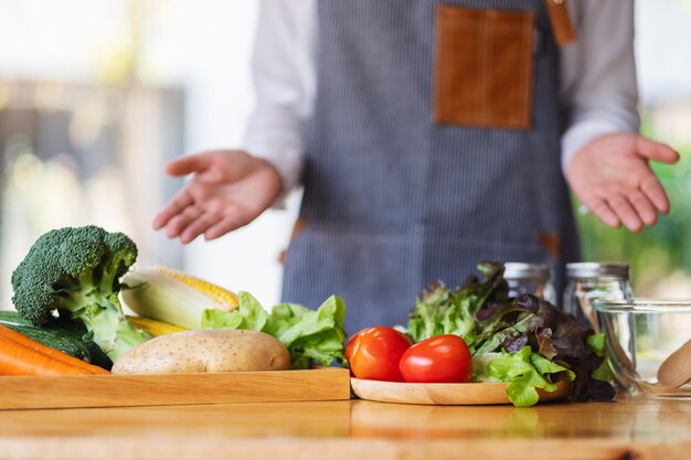 Close-upbeeld van een vrouwelijke chef-kok die verse gemengde groenten toont en bereidt om in de keuken te koken