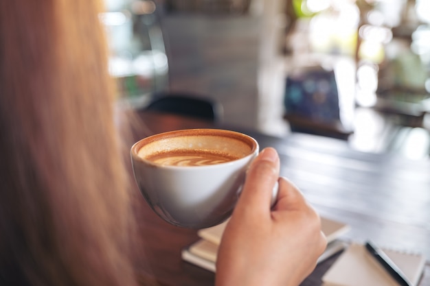 Close-upbeeld van een vrouwenholding en het drinken van hete koffie