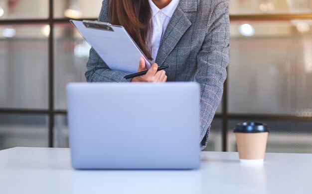 Close-upbeeld van een zakenvrouw die een laptopcomputer gebruikt terwijl ze op kantoor werkt