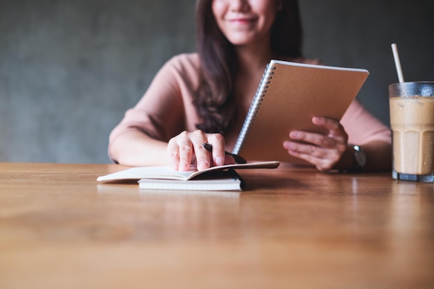 Close-upbeeld van een zakenvrouw die werkt en schrijft op een notitieboekje op houten tafel
