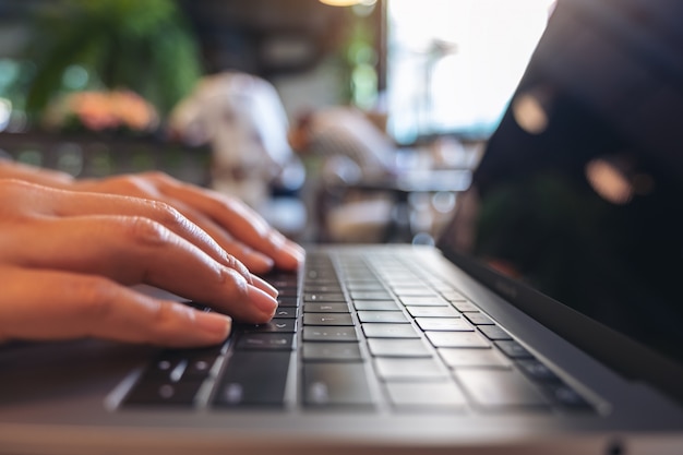 Close-upbeeld van handen die op laptop toetsenbord in koffie gebruiken en typen