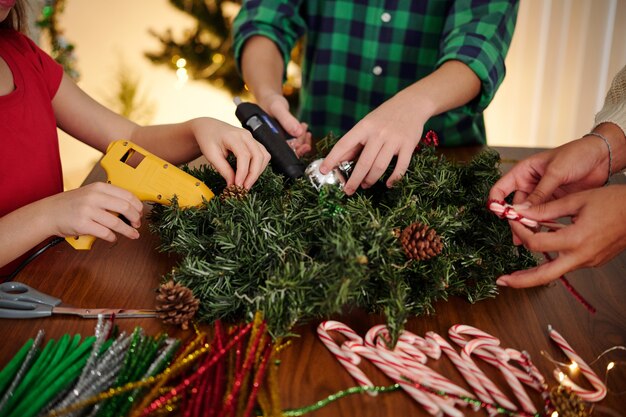 Close-upbeeld van jeugdvrienden die snuisterijen op de kroon van Kerstmis lijmen