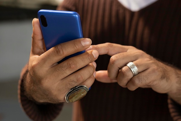 Close-upbeeld van mannelijke handen met ringen op hun vingers die berichten op het sociale netwerk typen met behulp van een blauw smart phone-concept