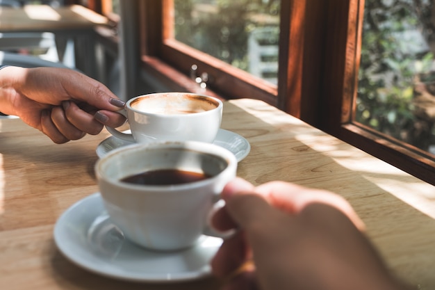 Close-upbeeld van twee mensen die en koffie in de ochtend houden drinken