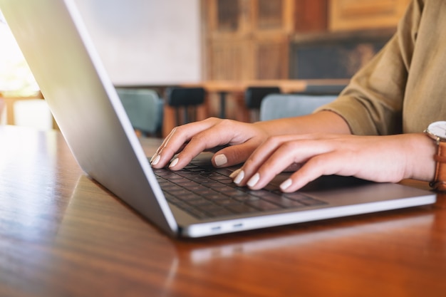 Close-upbeeld van vrouwenhanden die op laptop computertoetsenbord gebruiken en typen