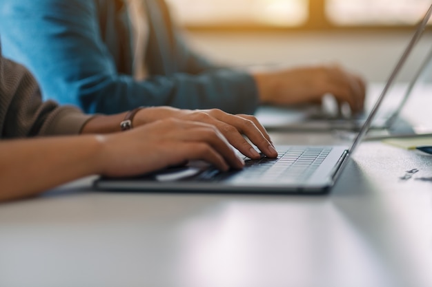 Close-upbeeld van zakenman die aan laptop computer samen in bureau gebruikt en werkt