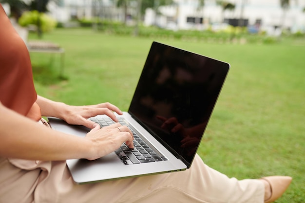 Close-upbeeld van zakenvrouw die op laptop werkt in stadspark