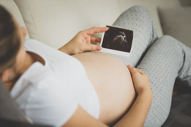 Close-upbeeld van zwangere vrouw die het beeld van het ultrasone klankembryo bekijkt