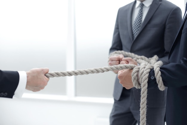 Close upbusinessman drags his business team by the rope photo\
with copy space