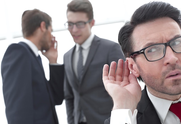 Photo close upbusinessman eavesdropping on conversation between colleaguesthe concept of gossip