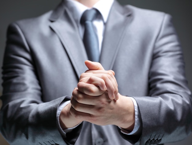 Close upbusinessman shows a sign with his handsisolated on black background