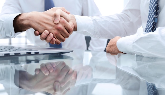Close upcolleagues shaking hands over a Desk