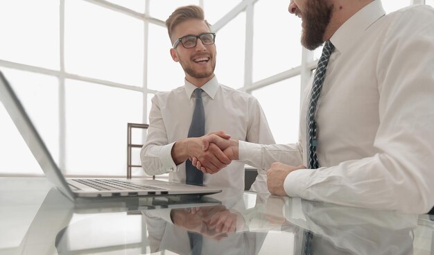 Close-upcollega's die handen schudden over een bureaufoto met kopieerruimte