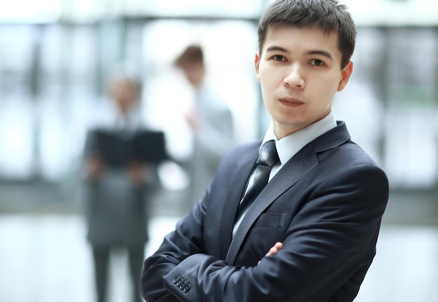 Close upconfident young businessman on blurred office background