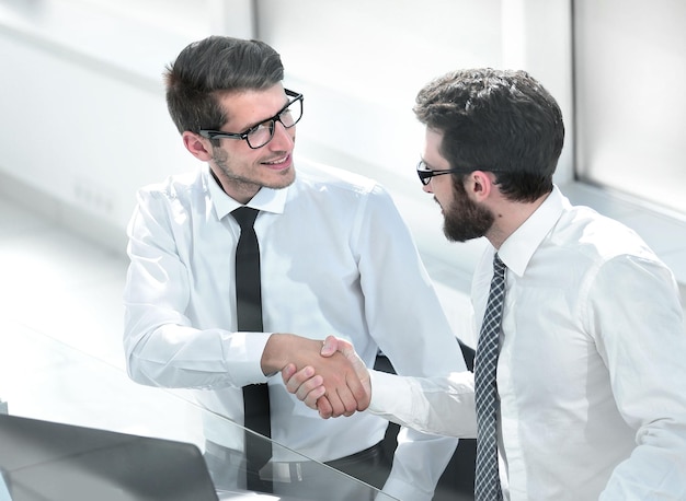 Close upemployees shaking hands at the Desk