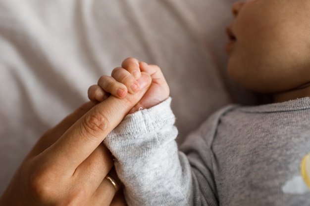 Close-upfoto van de hand die van de kleine baby de vinger van haar ouder houdt.