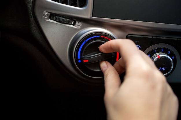 Close-upfoto van jonge vrouw die de schakelaar van de autoairconditioner draait